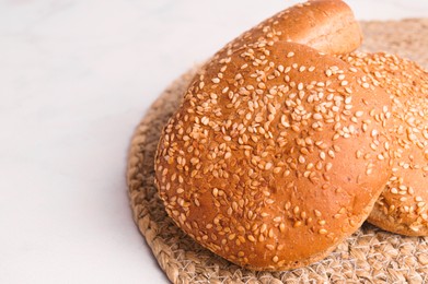 Photo of Fresh buns with sesame seeds on white marble table, closeup. Space for text