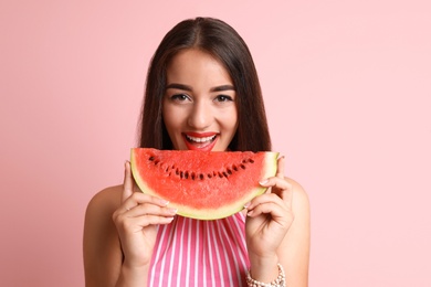 Beautiful young woman posing with watermelon on color background