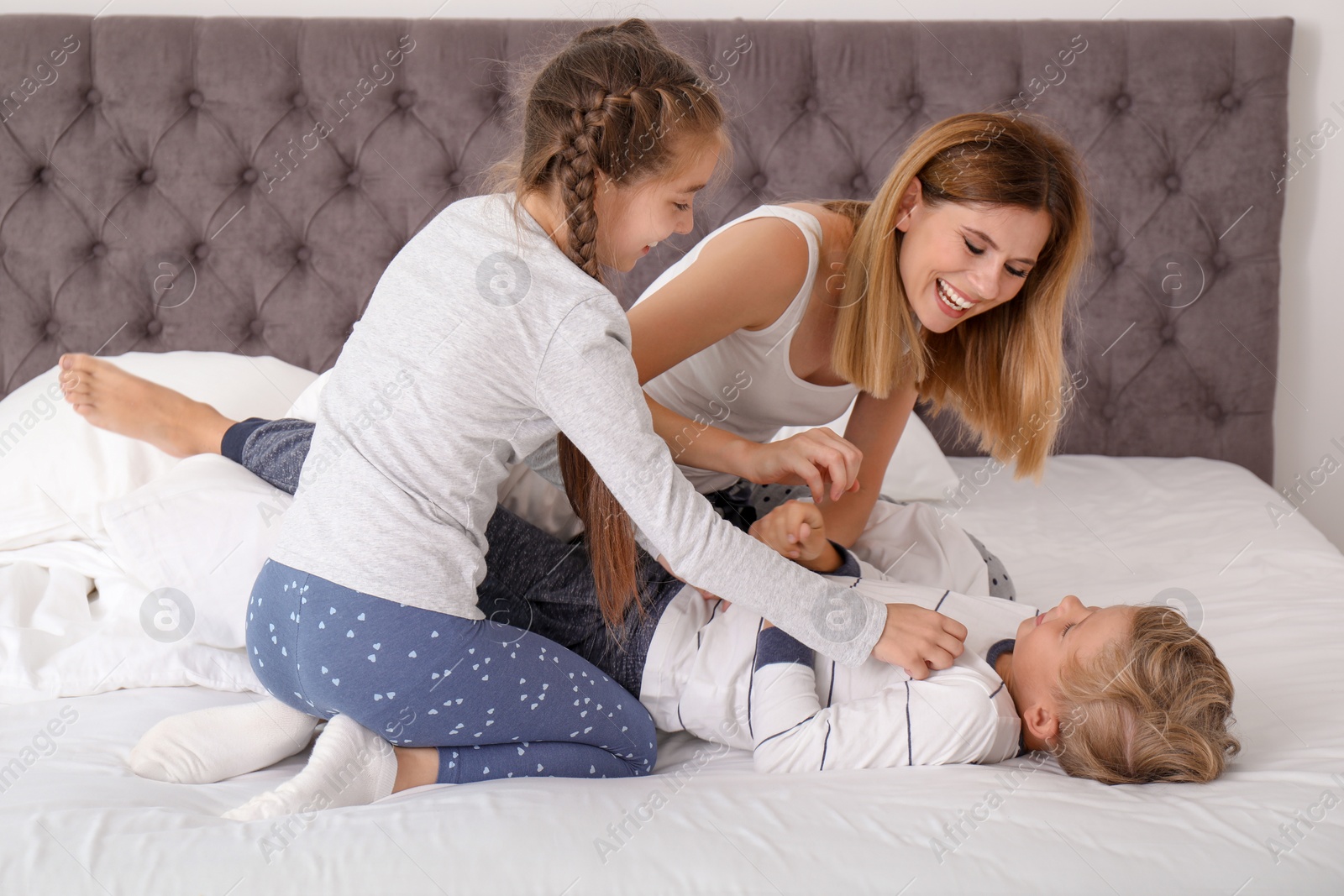 Photo of Woman playing with children in bedroom. Happy family