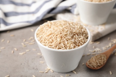 Photo of Uncooked brown rice in small bowl on table. Space for text