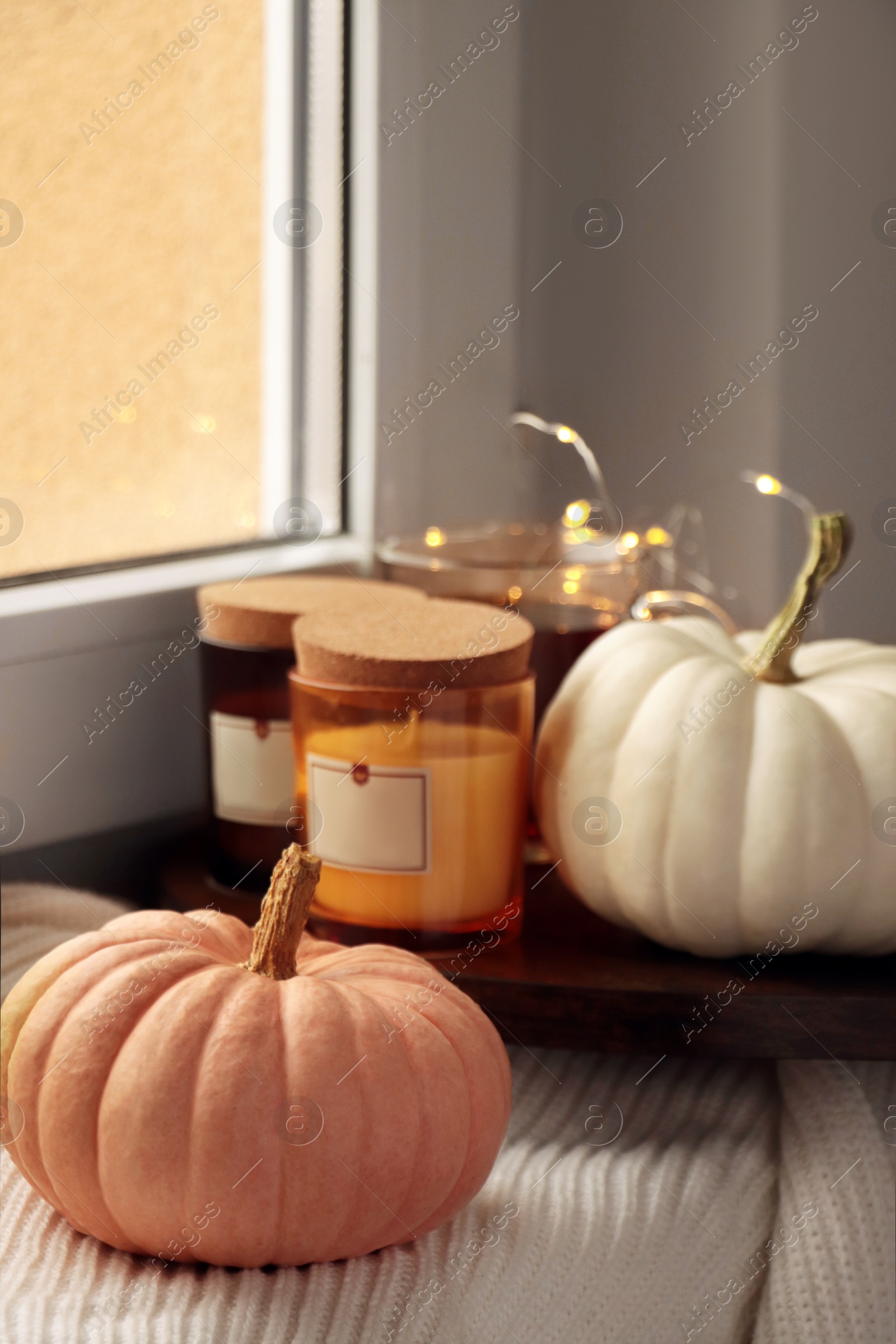 Photo of Beautiful pumpkins and scented candles on window sill indoors