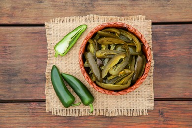 Photo of Fresh and pickled green jalapeno peppers on wooden table, top view