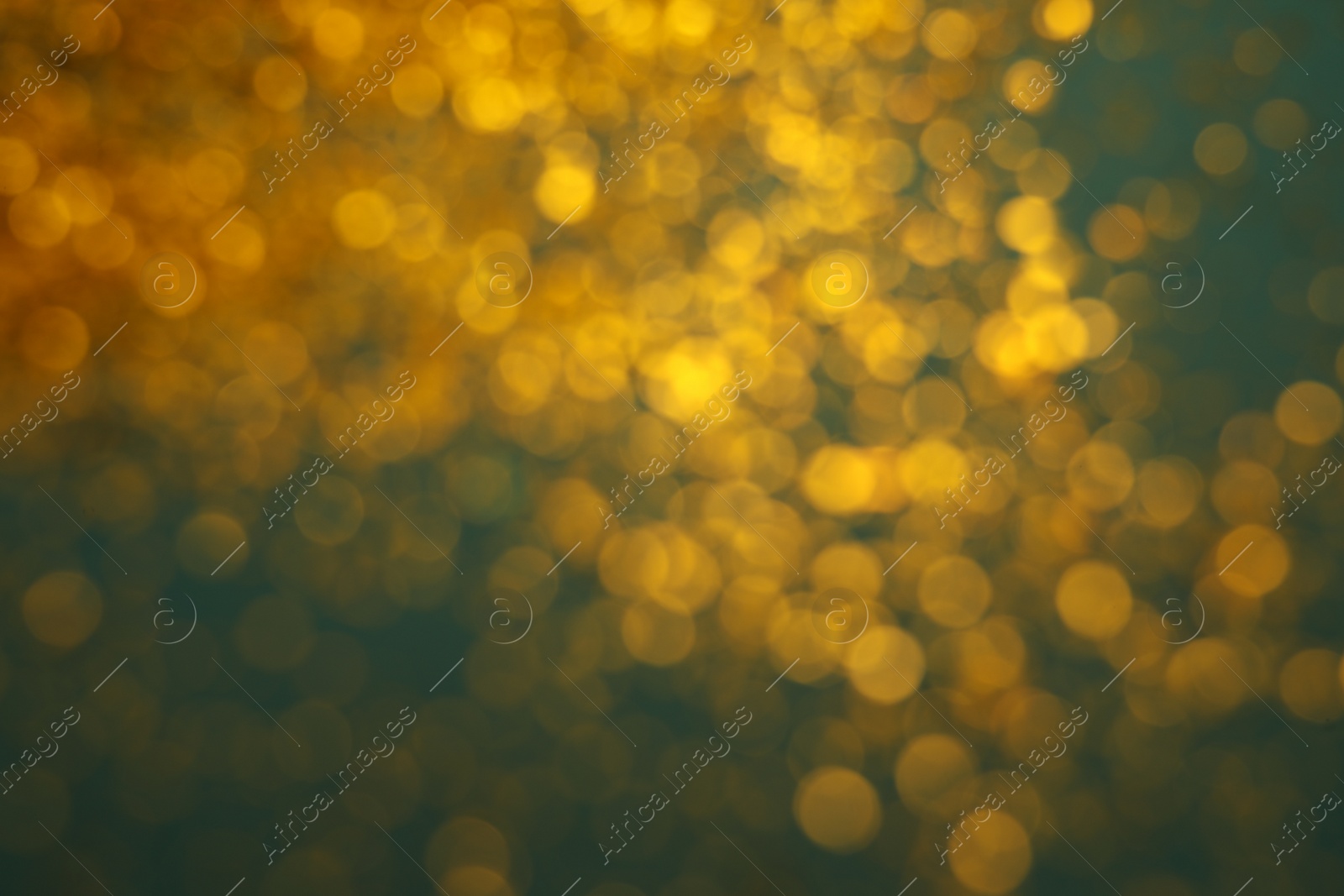 Photo of Blurred view of golden glitter on green background. Bokeh effect