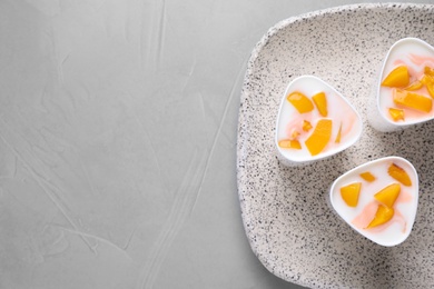 Plate with cups of peach yogurt on table, top view. Multi cooker recipe. Space for text