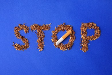 Photo of Word Stop made of dry tobacco and broken cigarette on blue background, flat lay. Quitting smoking concept
