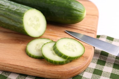Photo of Cucumbers, knife and cutting board on table, closeup