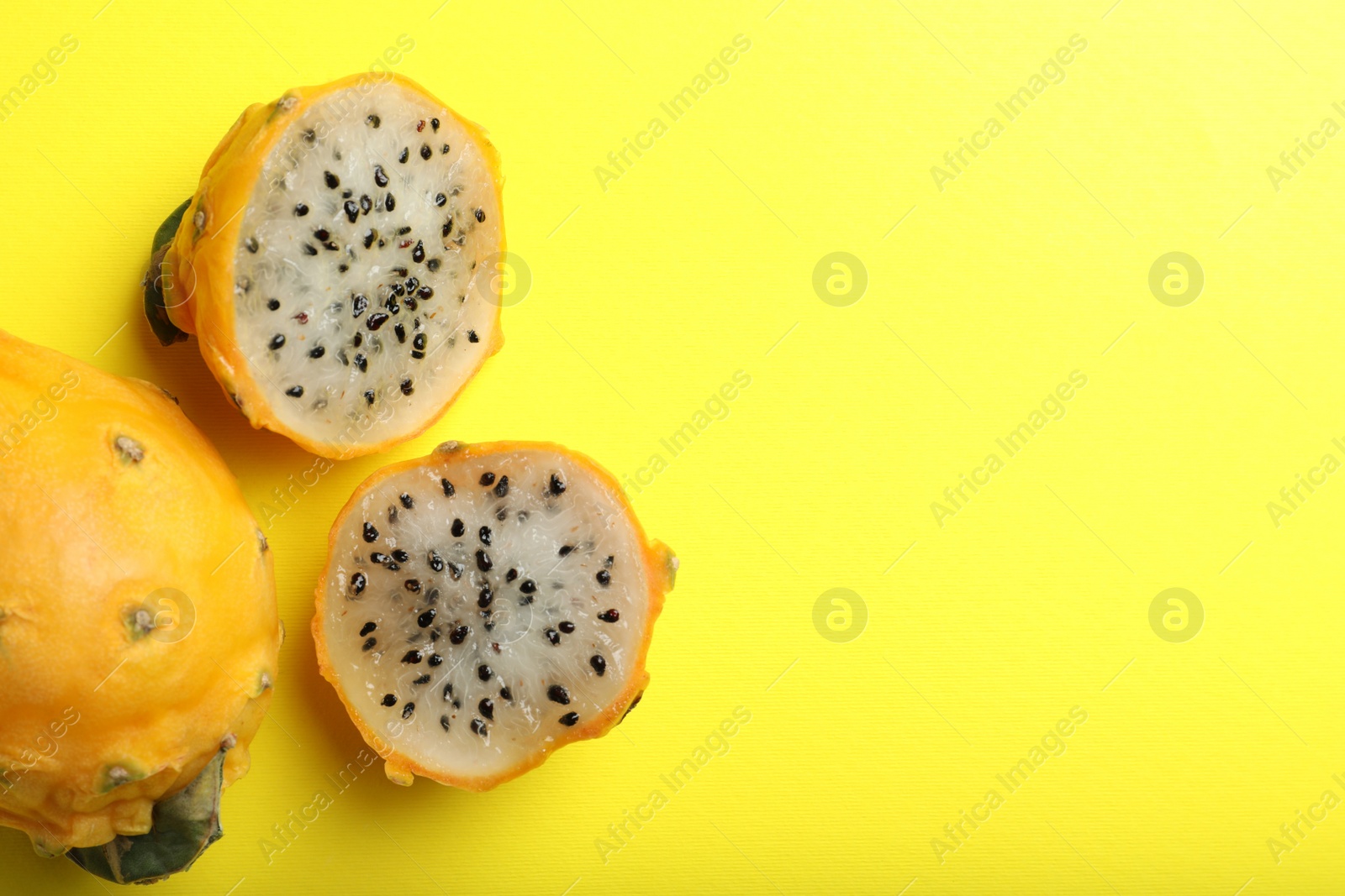 Photo of Delicious cut and whole dragon fruits (pitahaya) on yellow background, flat lay. Space for text