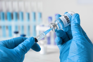 Doctor filling syringe with vaccine against Covid-19 indoors, closeup