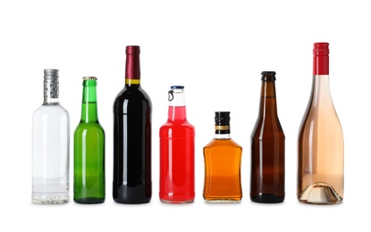 Bottles with different alcoholic drinks on white background