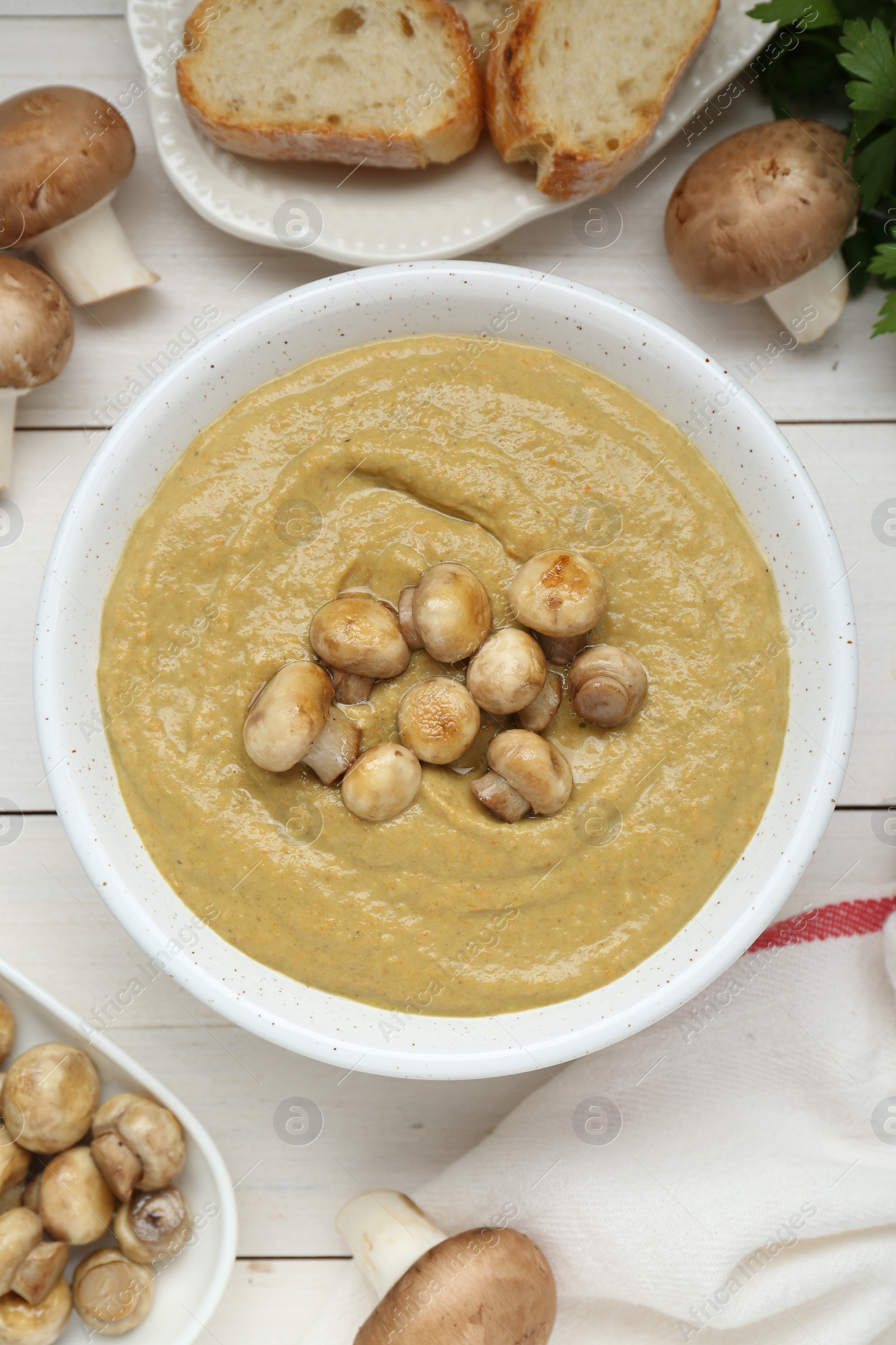 Photo of Delicious mushroom cream soup on white wooden table, flat lay