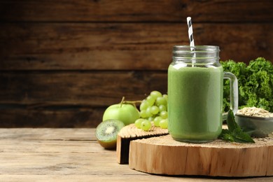 Photo of Mason jar of fresh green smoothie and ingredients on wooden table, space for text