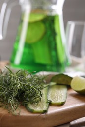 Photo of Fresh tarragon leaves and slices of cucumber on wooden board, closeup