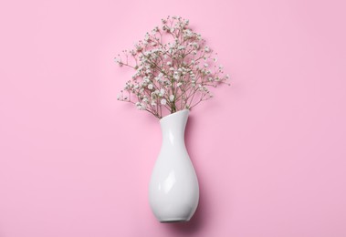 Photo of Beautiful gypsophila in white vase on pink background, top view