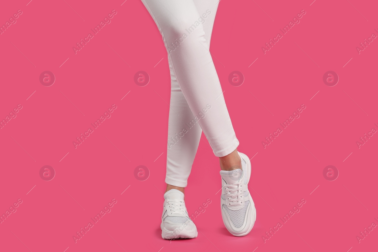 Photo of Woman wearing sneakers on pink background, closeup