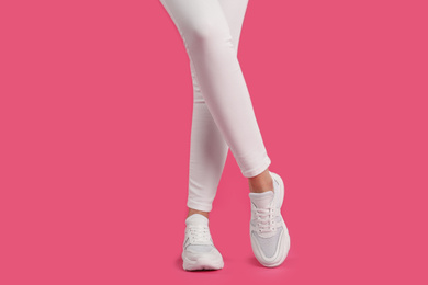 Woman wearing sneakers on pink background, closeup