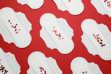 Photo of Menstrual pads with sequins on red background, flat lay