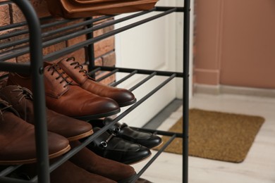 Rack with different shoes near red brick wall in hallway, closeup