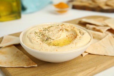 Photo of Delicious hummus served with pita chips on wooden board
