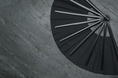 Photo of Stylish black hand fan on grey background, top view. Space for text