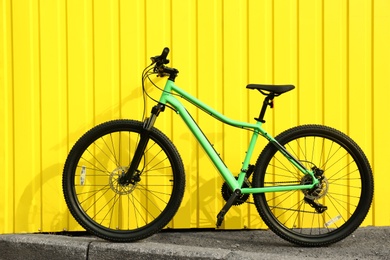 Modern bicycle near yellow metal fence outdoors