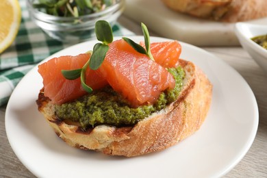 Photo of Delicious bruschetta with salmon and pesto sauce on table, closeup