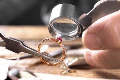 Photo of Male jeweler examining ruby ring in workshop, closeup view