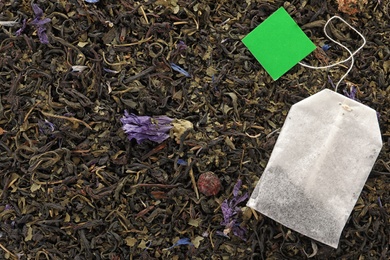 Photo of Tea bag on dry leaves, top view with space for text