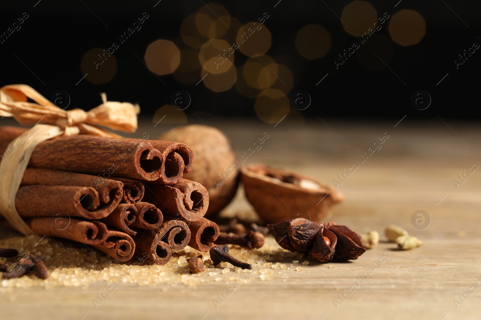 Photo of Different spices on wooden table against black background, closeup