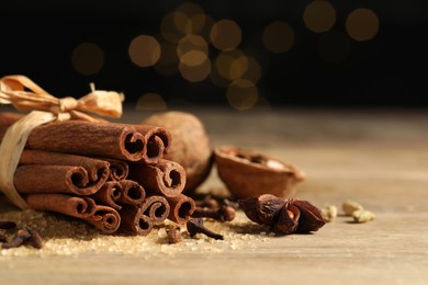 Different spices on wooden table against black background, closeup