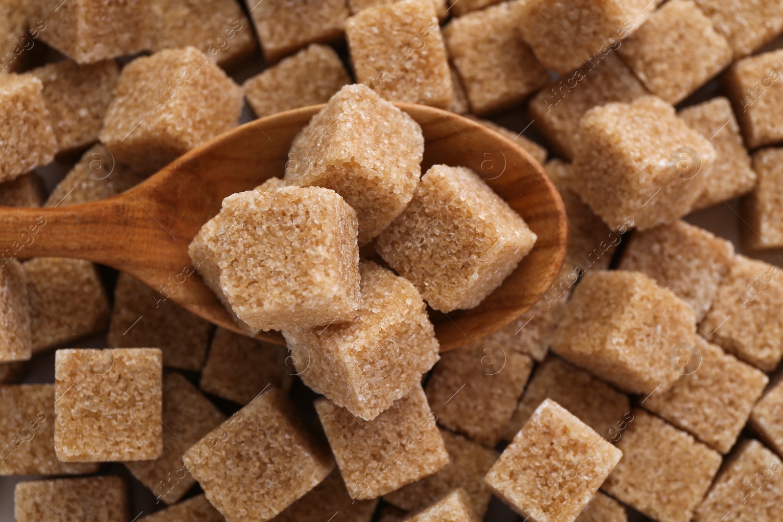 Photo of Wooden spoon on brown sugar cubes, above view