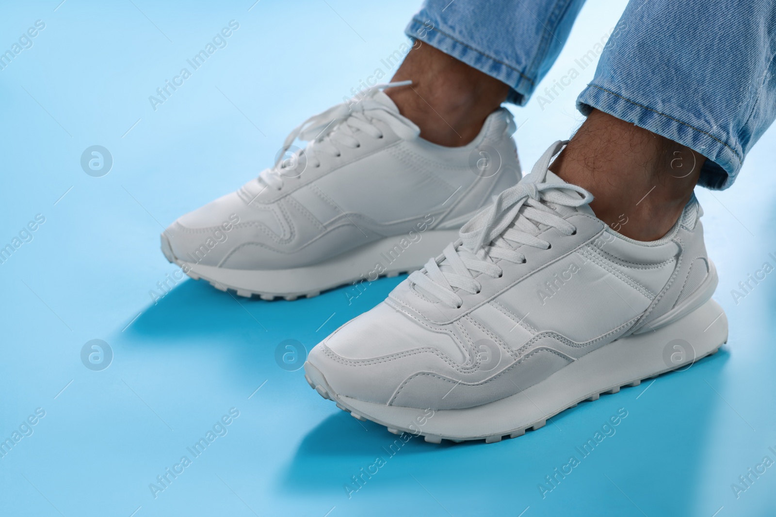 Photo of Man wearing stylish sneakers on light blue background, closeup