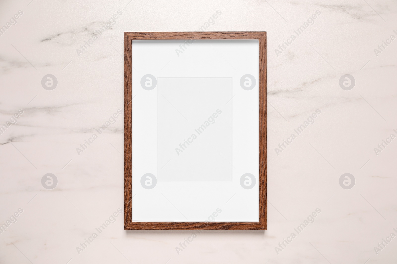 Photo of Empty photo frame on white marble background, top view. Space for design