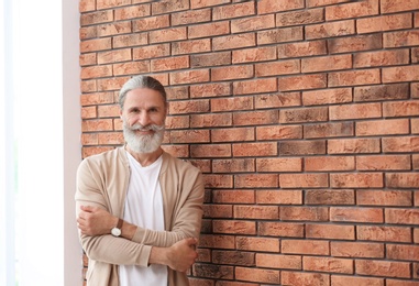 Photo of Portrait of handsome mature man near brick wall