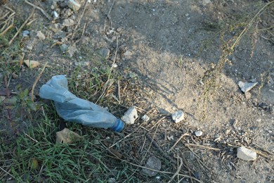 Photo of Used plastic bottle outdoors, space for text. Environmental pollution concept