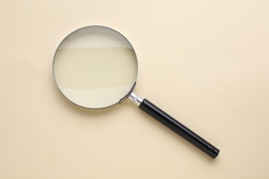 Photo of Magnifying glass on beige background, top view