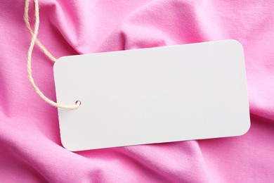 Photo of Cardboard tag with space for text on pink fabric, top view