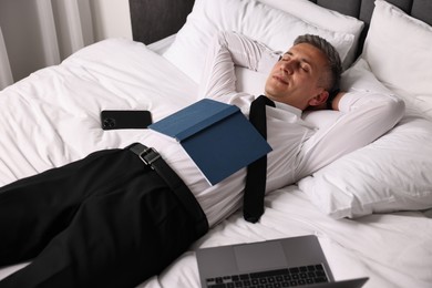 Businessman in office clothes sleeping on bed indoors