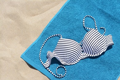 Photo of Blue beach towel and swimsuit on sand, top view