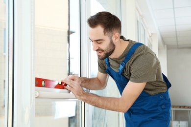 Photo of Construction worker using bubble level while installing window indoors