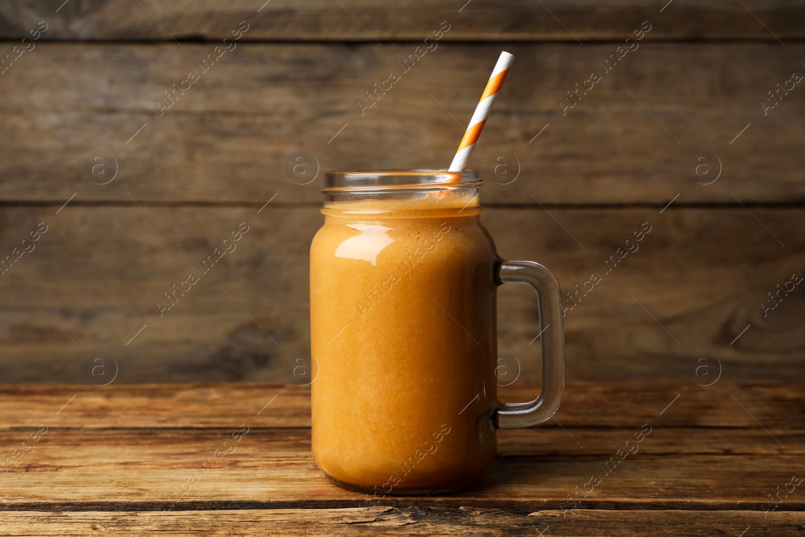 Photo of Mason jar with delicious fruit smoothie on wooden table