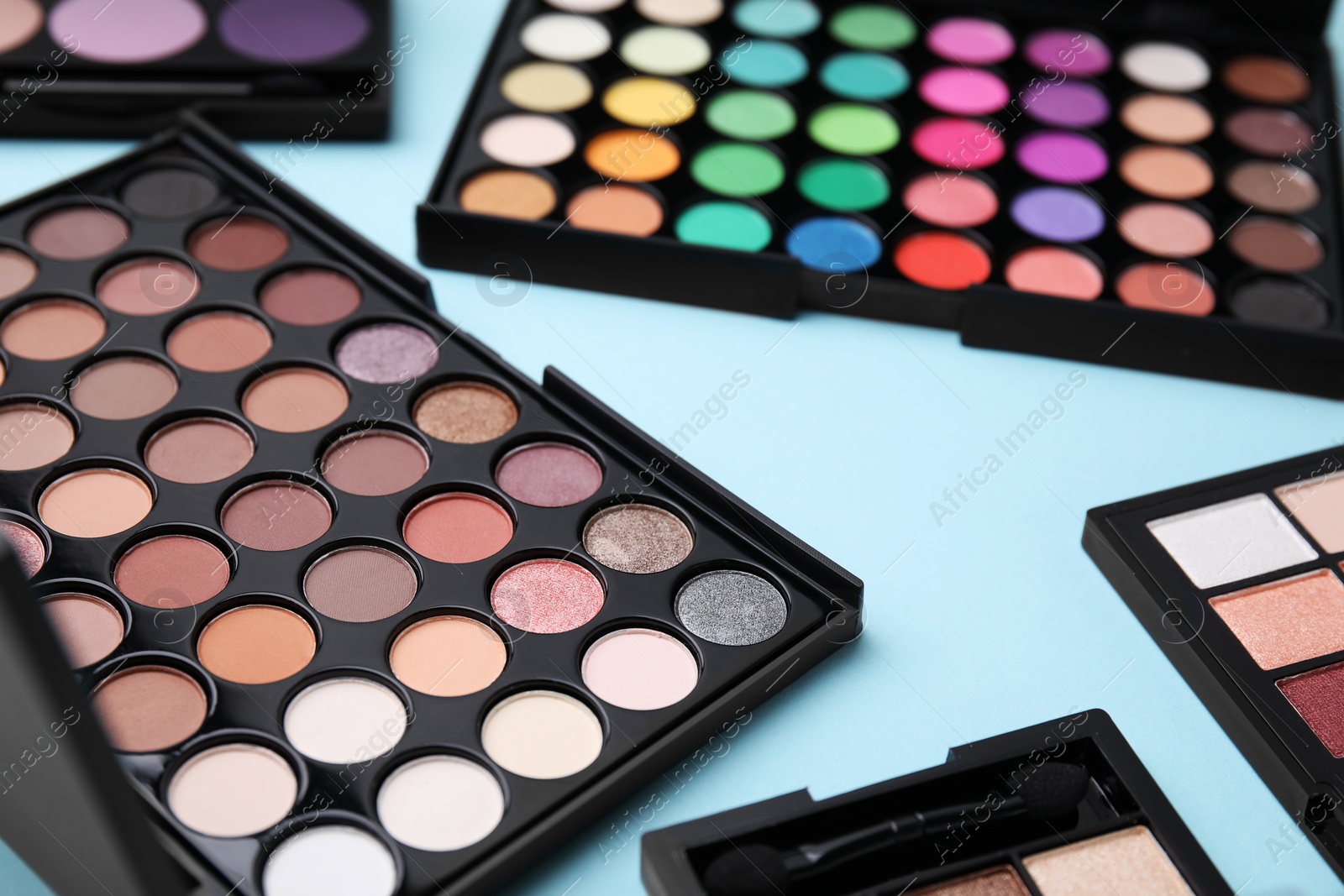 Photo of Beautiful eye shadow palettes on light blue background