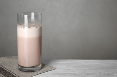 Photo of Glass with protein shake on white wooden table. Space for text