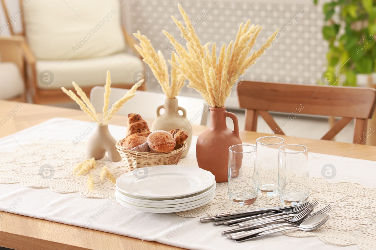 Photo of Clean dishes, dry spikes and fresh pastries on table in stylish dining room