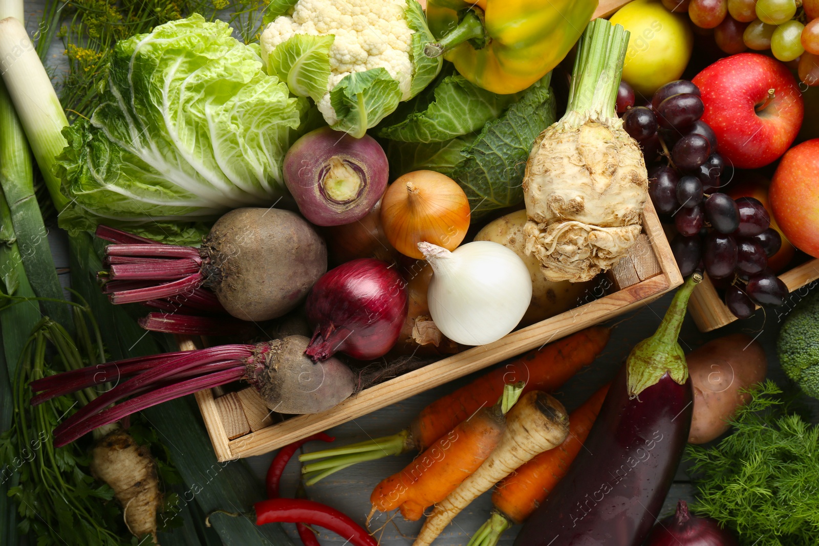 Photo of Different fresh vegetables and fruits in crates on grey wooden table, flat lay. Farmer harvesting