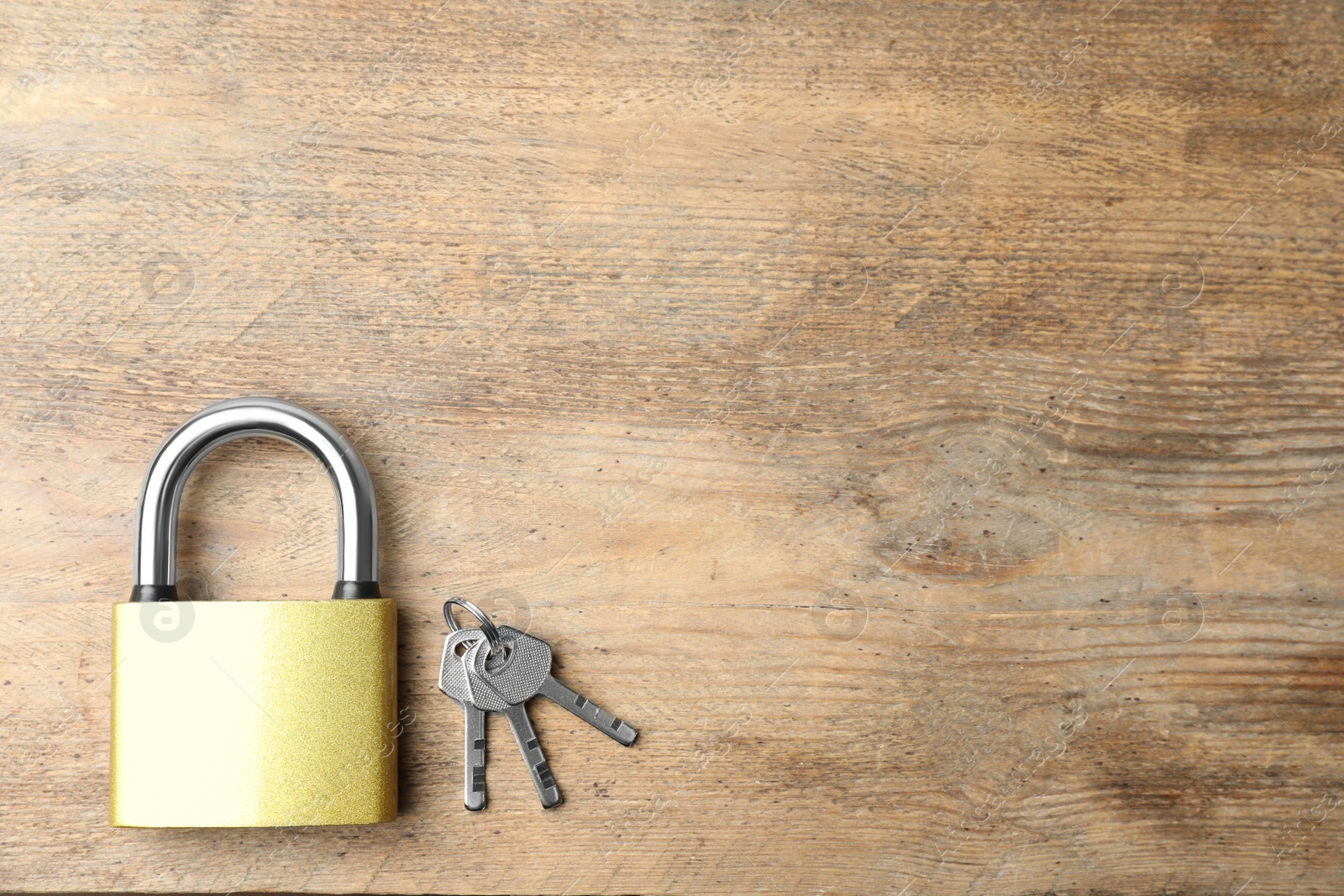 Photo of Steel padlock and keys on wooden background, top view with space for text. Safety concept