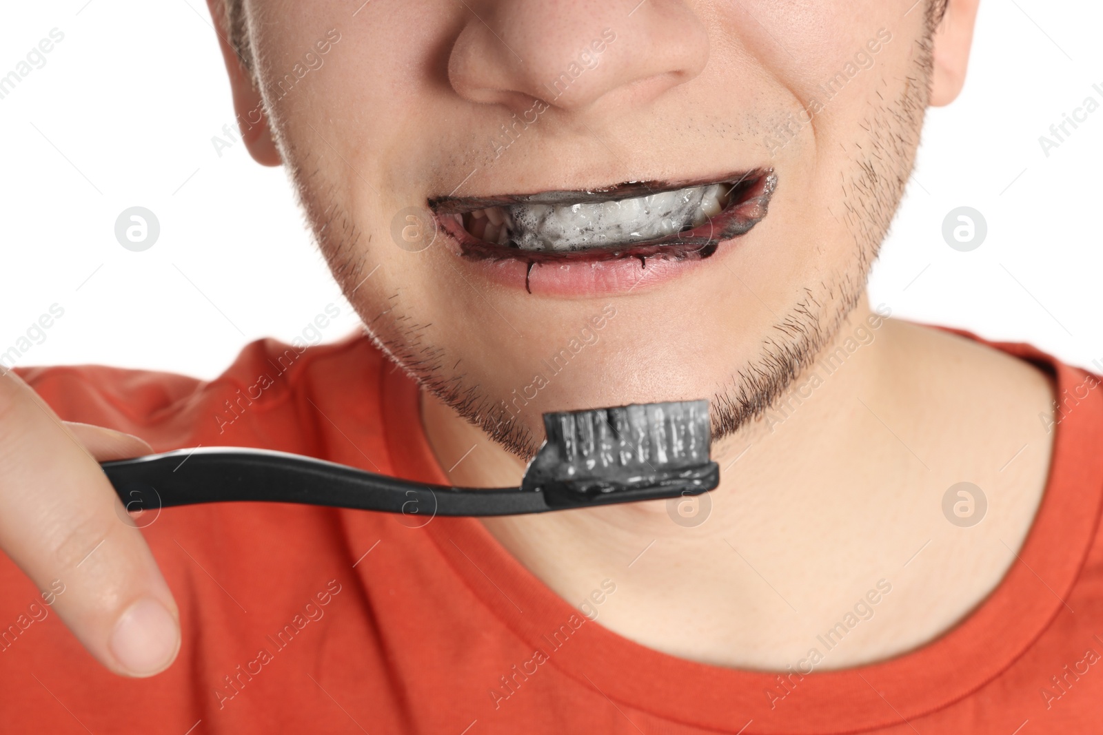 Photo of Man brushing teeth with charcoal toothpaste on white background, closeup