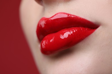 Closeup view of beautiful young woman with perfect lips makeup on red background