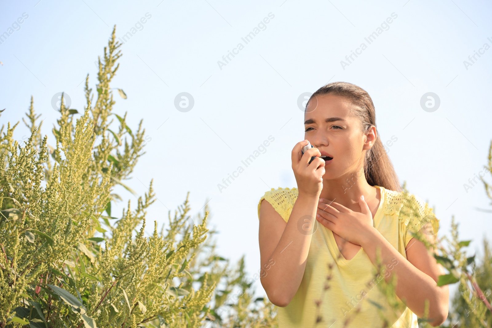 Photo of Young woman with inhaler suffering from ragweed allergy outdoors