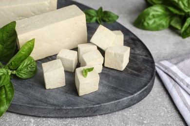 Photo of Delicious tofu with basil on grey table, closeup
