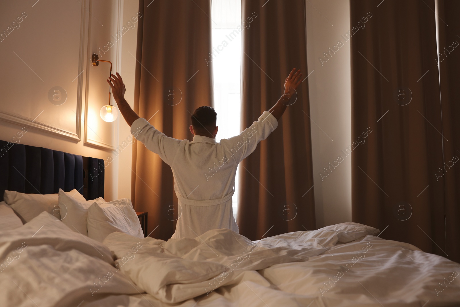 Photo of Man waking up in hotel room, back view